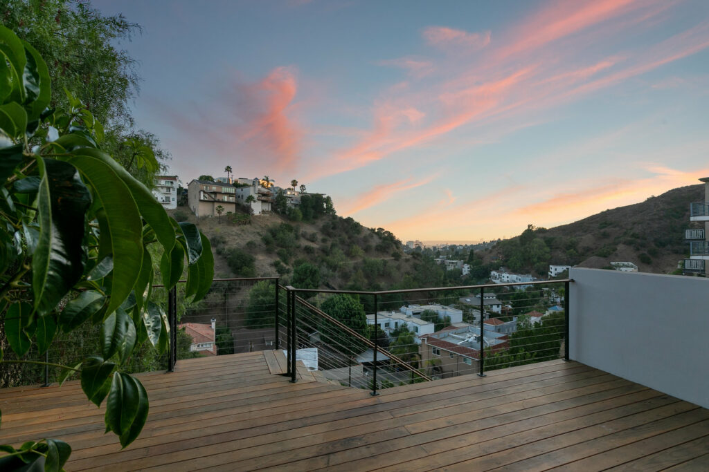 Sunset view from hillside deck with lush foliage.