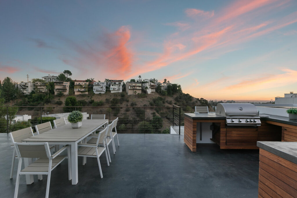 Rooftop patio with dining set and grill at dusk.
