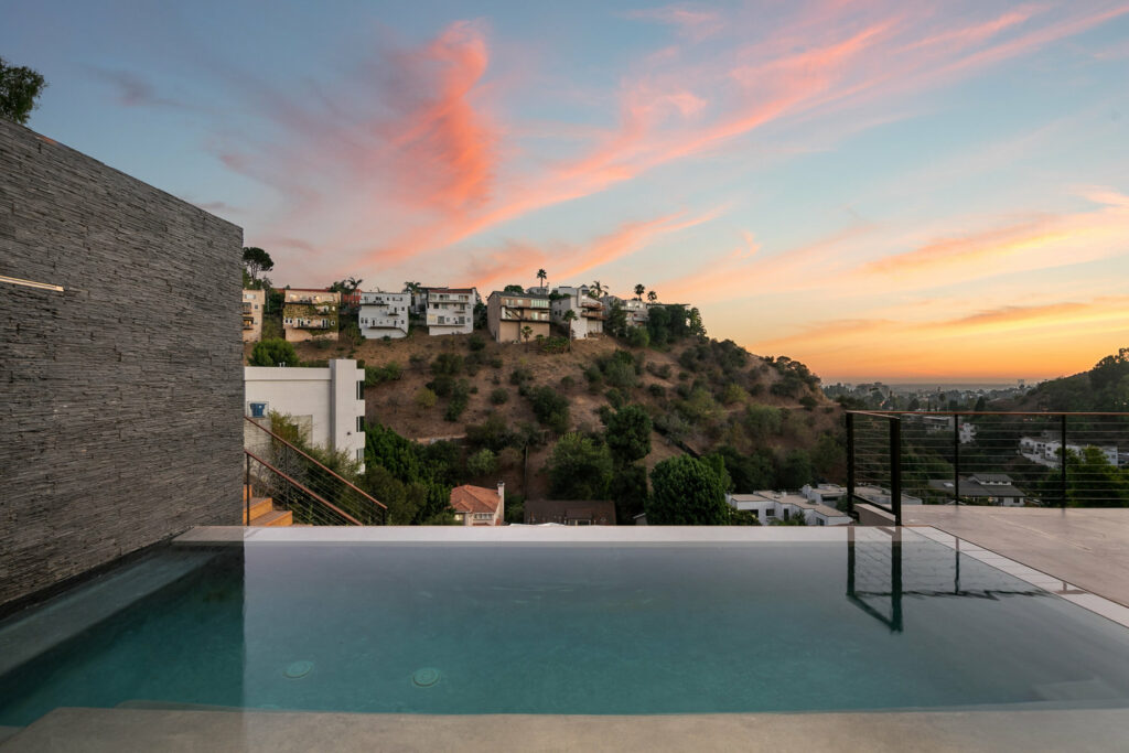 Infinity pool overlooking hills at sunset