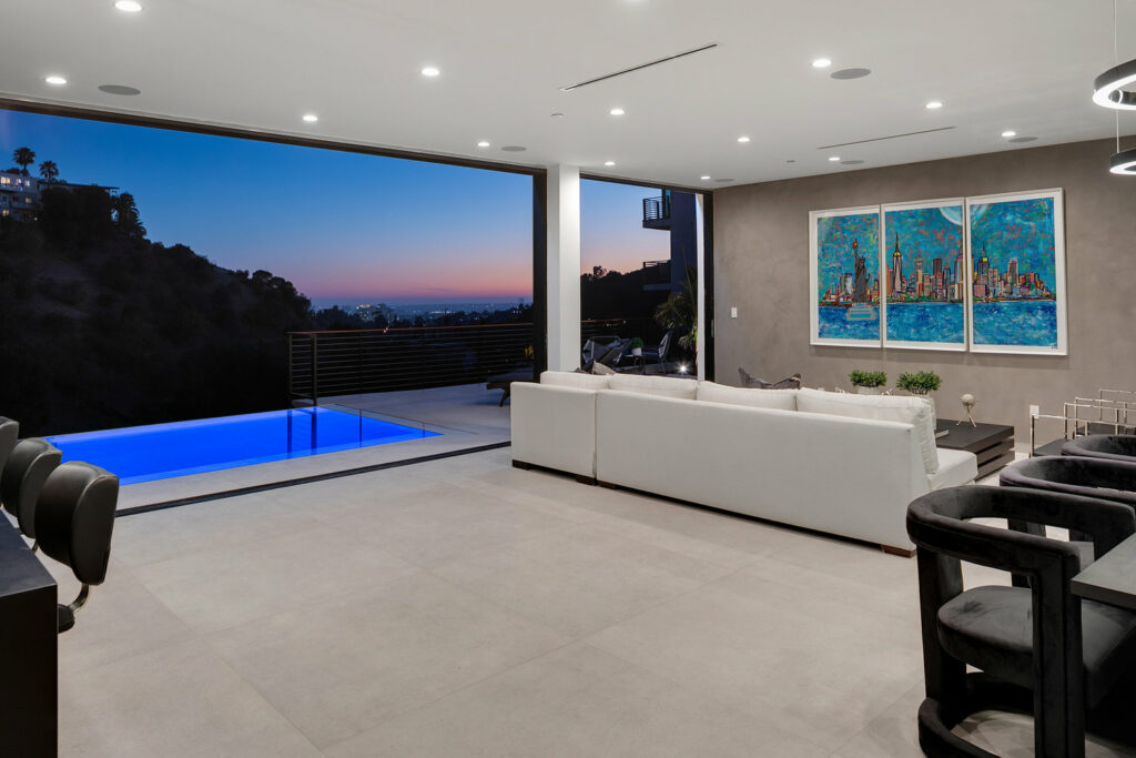 Modern living room with pool and sunset view.