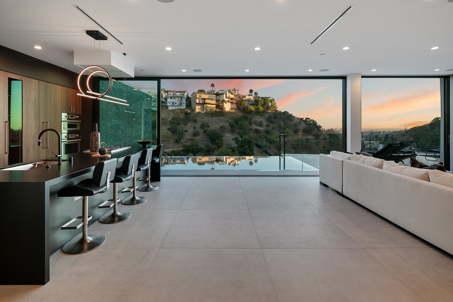 Modern kitchen with sunset view through large window.