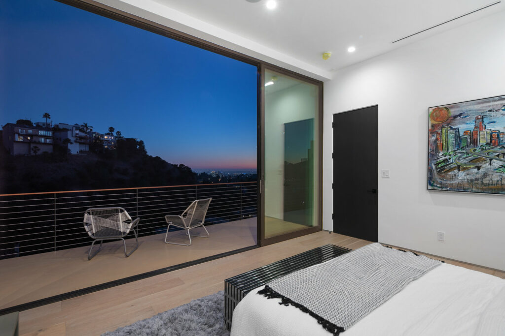 Modern bedroom with cityscape view at dusk