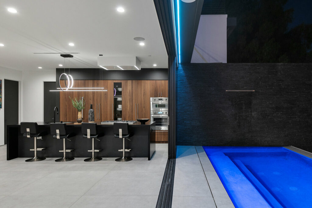 Modern kitchen interior with adjacent pool lighting.