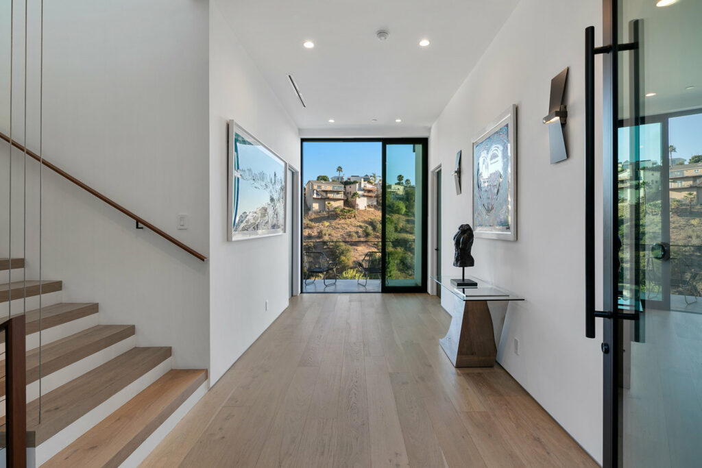 Modern hallway with art and scenic view through window.