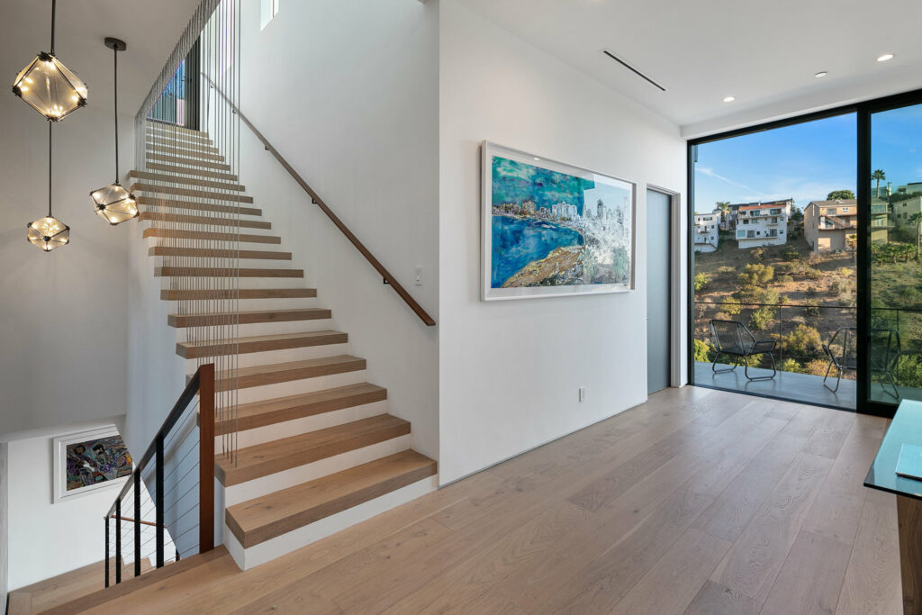 Modern interior with stairs, art, and hillside view.
