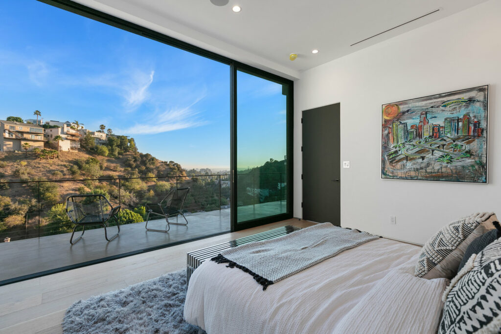 Modern bedroom with scenic hillside view and art décor.