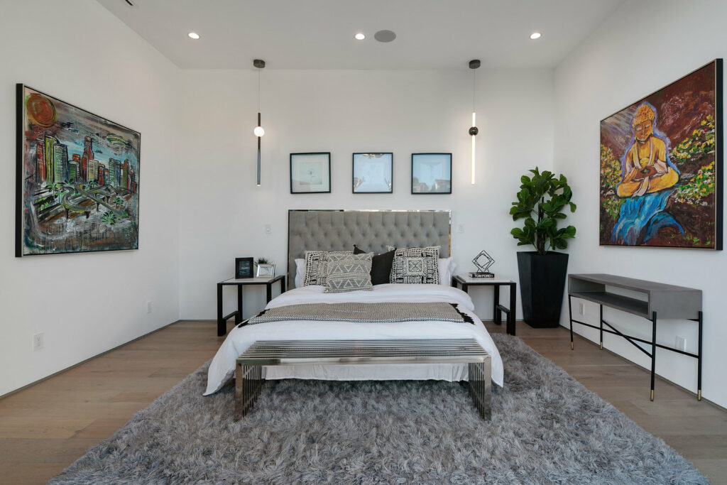 Modern bedroom with art decor and plush grey rug.