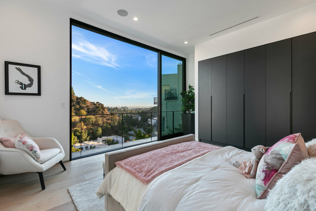 Modern bedroom with large window overlooking scenic view.