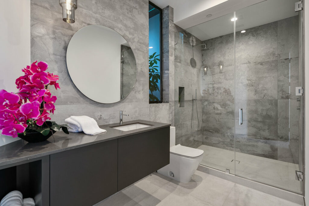 Modern bathroom with gray tiles and walk-in shower.