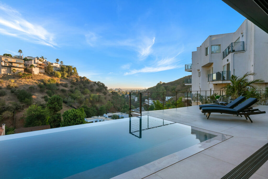 Luxury home infinity pool with hillside view at sunset.