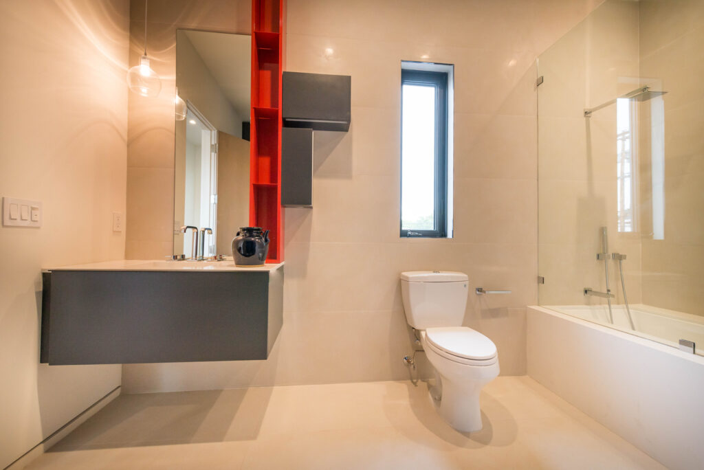 Modern bathroom with red accents and natural light.