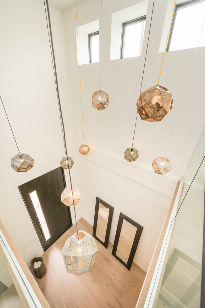 Modern geometric pendant lights in bright hallway.