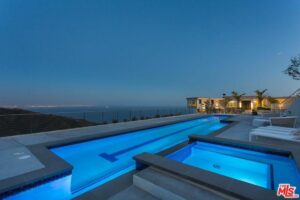 Luxury home with infinity pool overlooking city lights at dusk