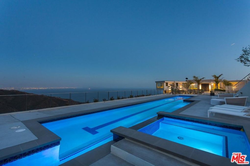 Luxury home with infinity pool overlooking city lights at dusk