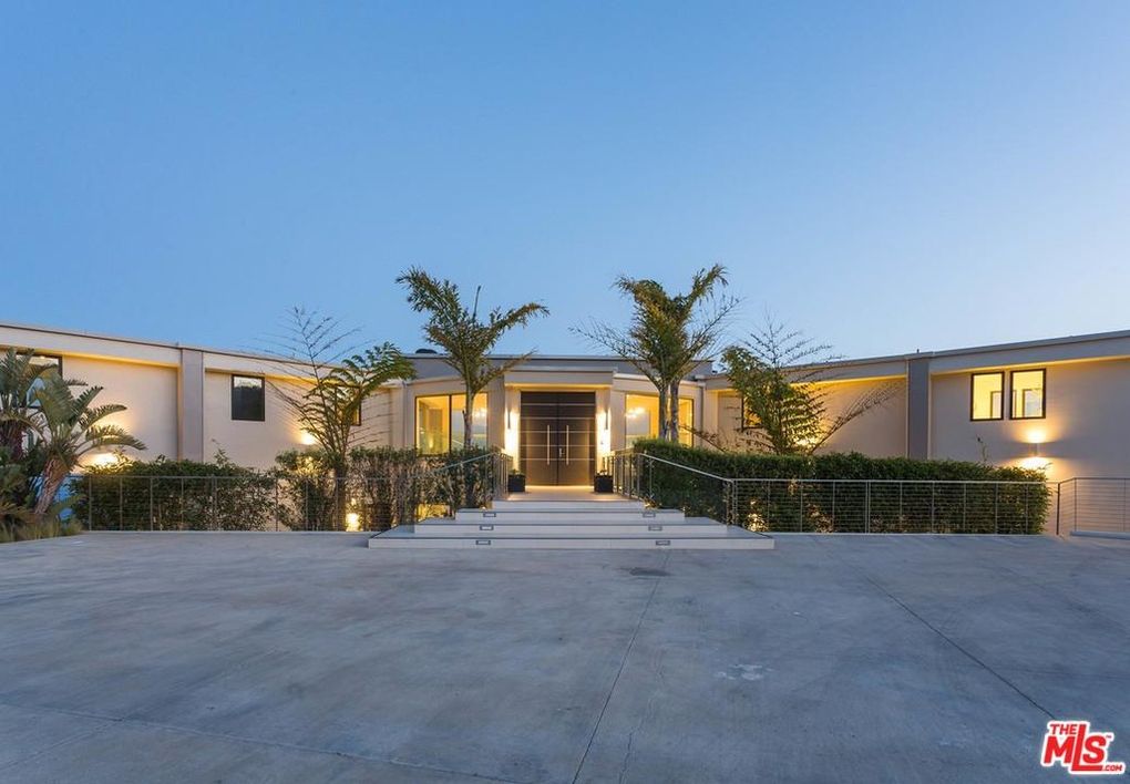 Modern home exterior at dusk with lights.