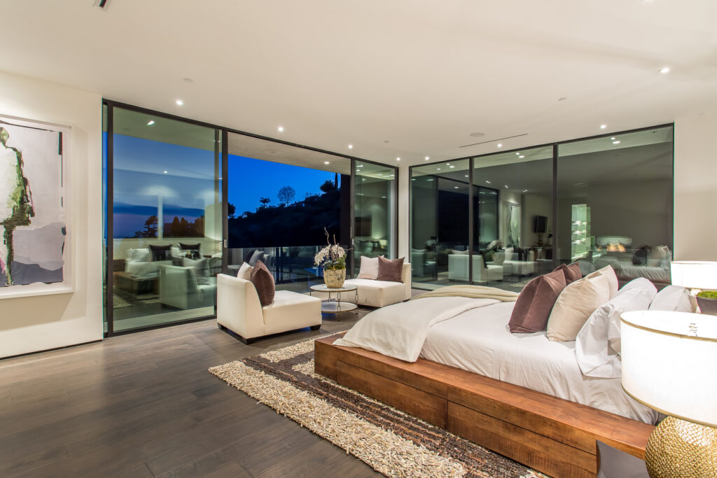Modern bedroom with large windows and sunset view.