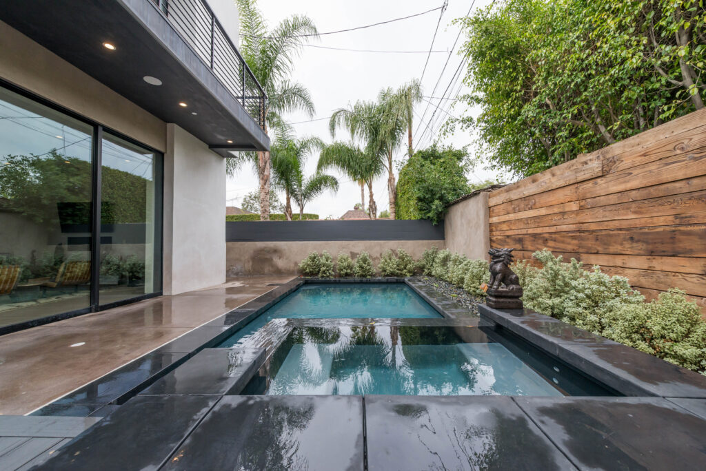 Modern backyard with pool and wooden fence.