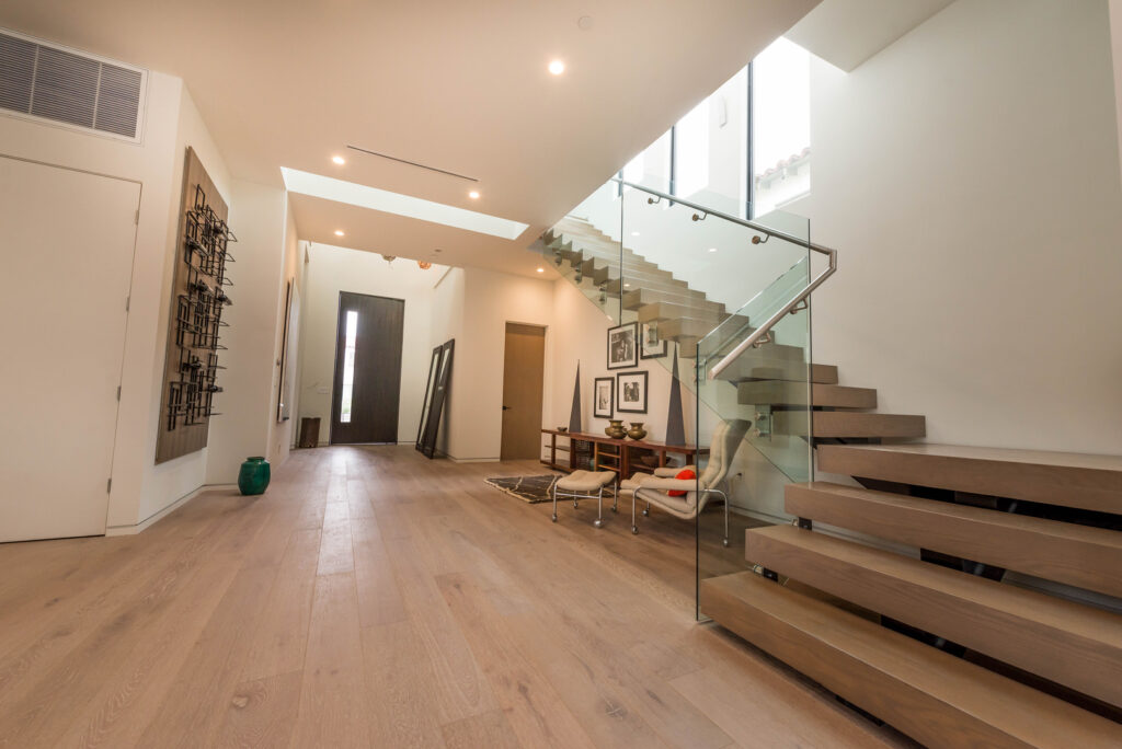 Modern hallway with floating staircase and art decorations.