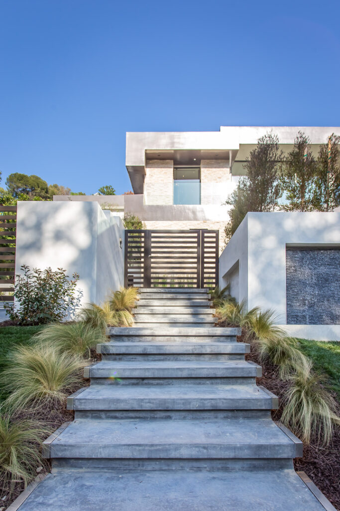 Modern house exterior with concrete staircase and landscaping.