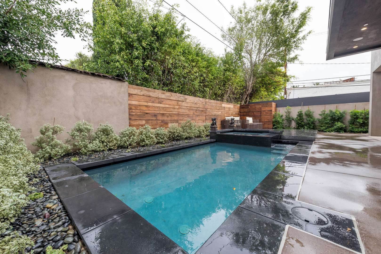 Modern backyard with swimming pool and wooden fence.