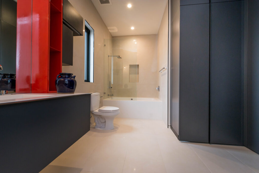 Modern bathroom interior with red cabinet and white tub