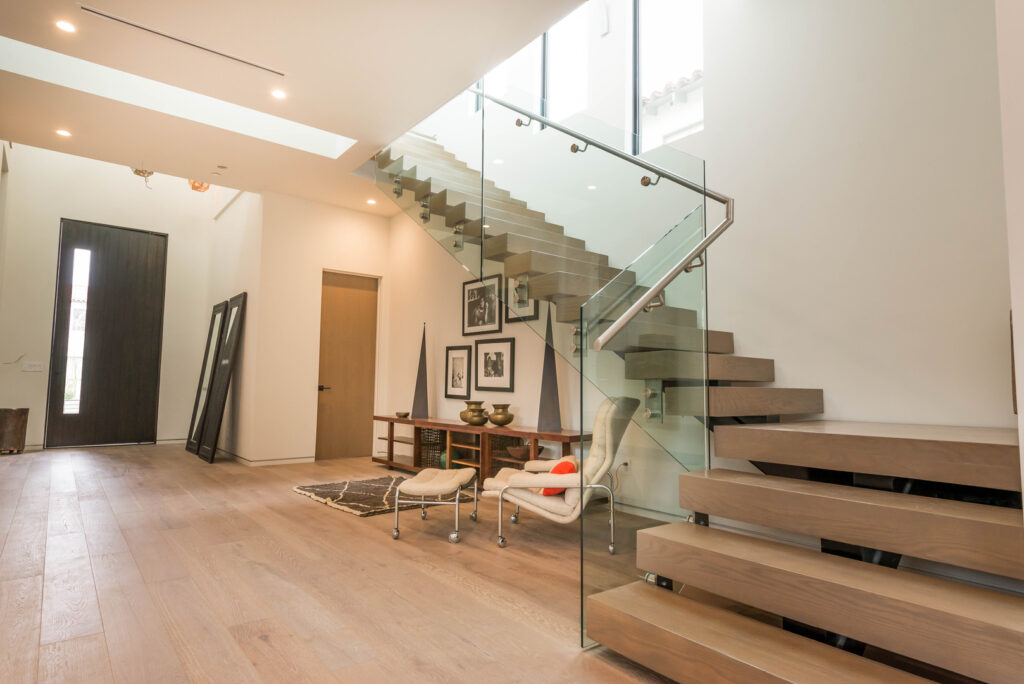 Modern interior with floating staircase and glass balustrade.