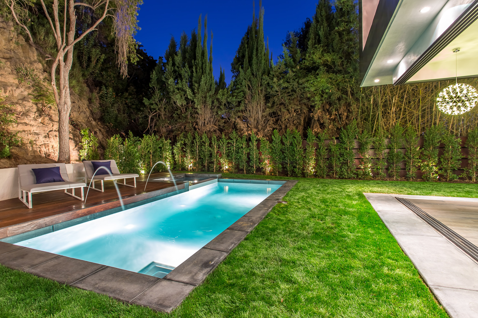 Luxurious backyard pool with lighting at night.