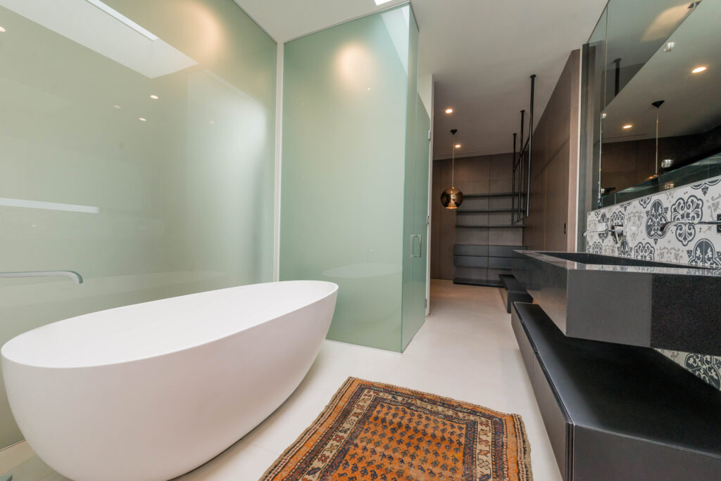 Modern bathroom with freestanding tub and patterned accent wall.