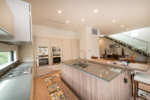 Modern kitchen interior with island and staircase.