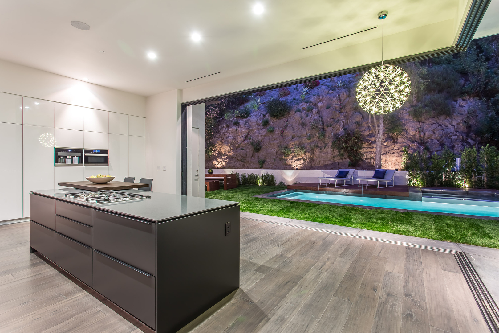 Modern kitchen interior with pool view at dusk.