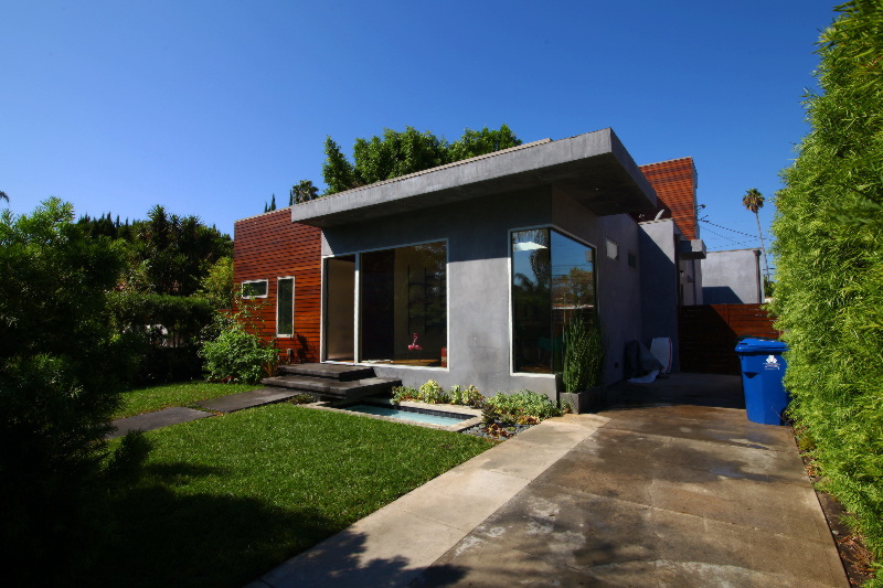 Modern house with large windows and green lawn.