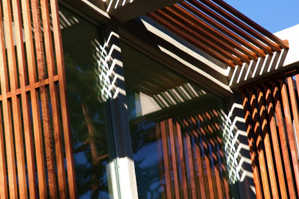 Modern building with wooden slats and shadow patterns.