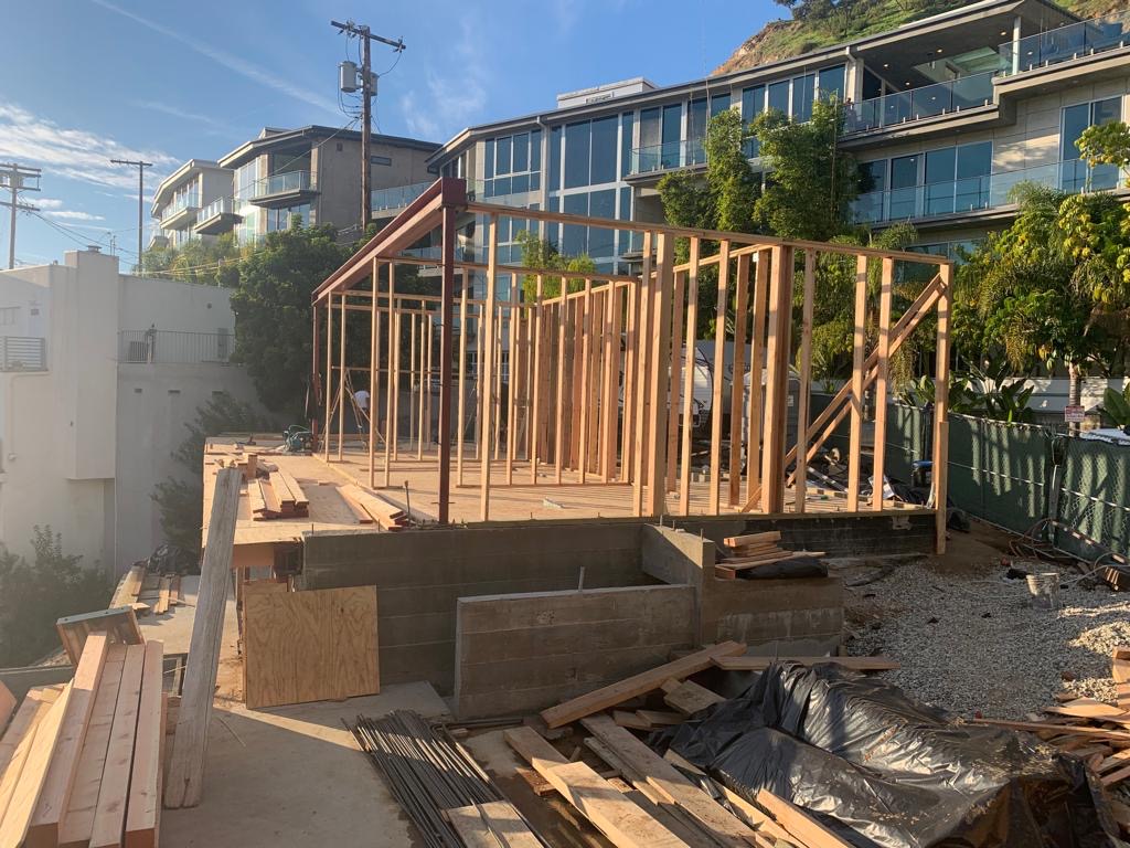 Wooden house frame under construction with materials around.