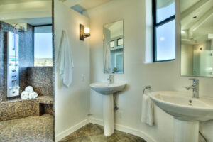 Modern bathroom with shower and dual sinks.