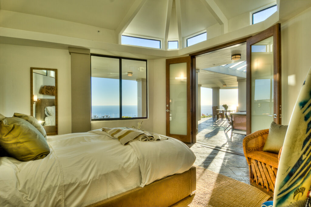 Beachfront bedroom with large windows and balcony access.