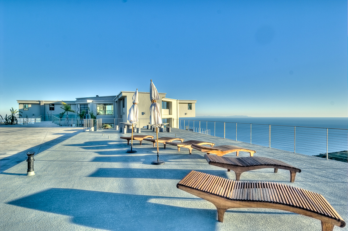 Luxurious seaside villa patio with sun loungers and view.
