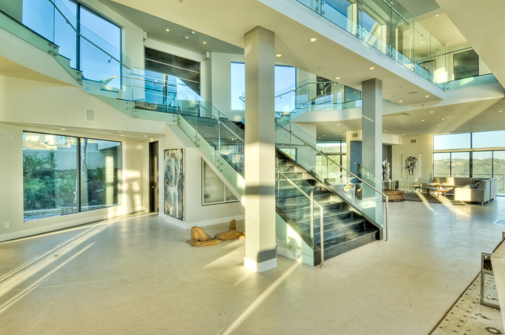 Modern spacious home interior with glass staircase.