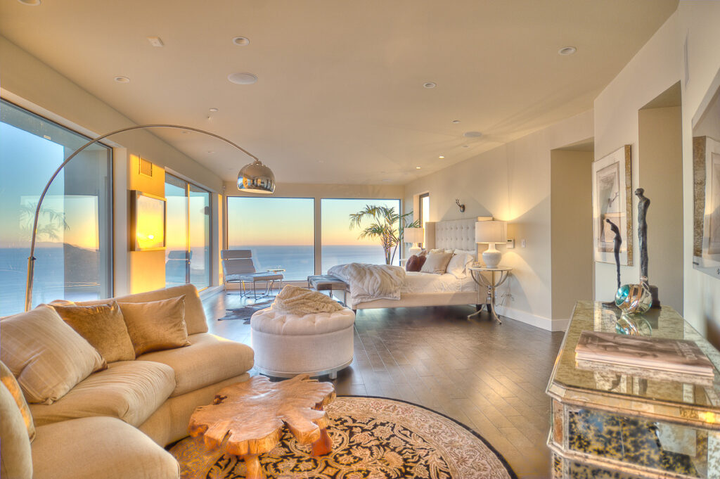 Luxurious bedroom with ocean sunset view and modern decor.