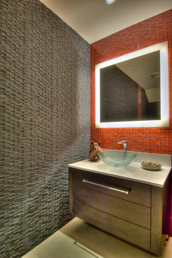 Modern bathroom with textured walls and illuminated mirror.