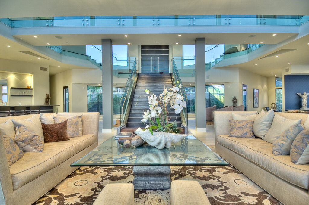 Modern living room with glass staircase and elegant furnishings.