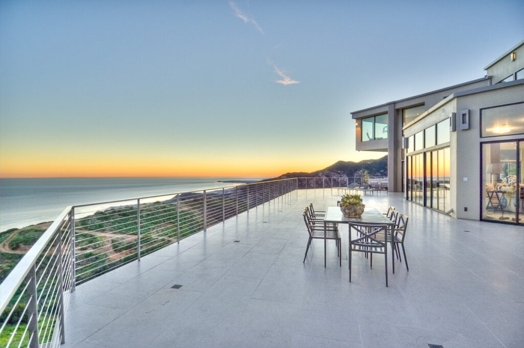 Oceanfront patio with dining setup at sunset.