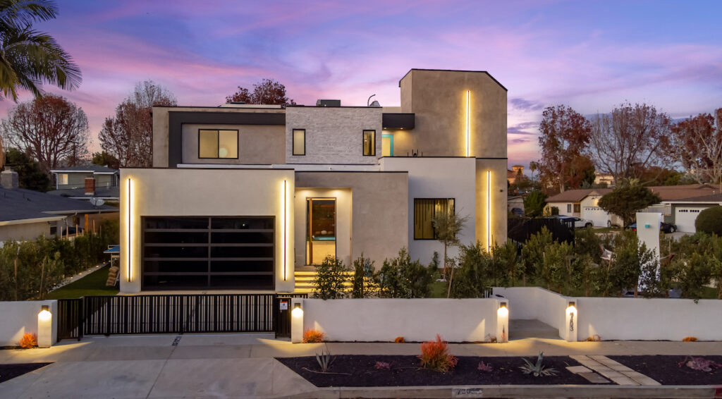 Modern house exterior at twilight with lights.