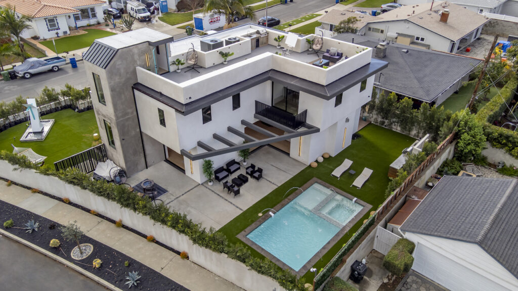 Modern house with pool aerial view in suburban neighborhood.