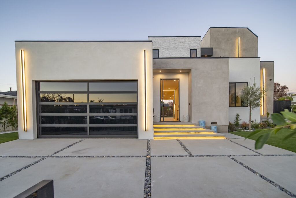 Modern home exterior at dusk with illuminated entrance.