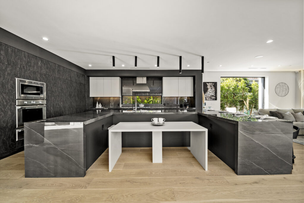 Modern kitchen interior with marble finishes and wooden floors.