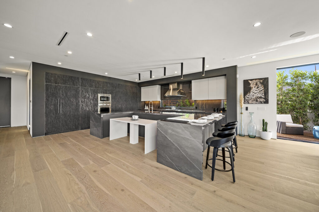 Modern kitchen interior with marble island and hardwood floors.