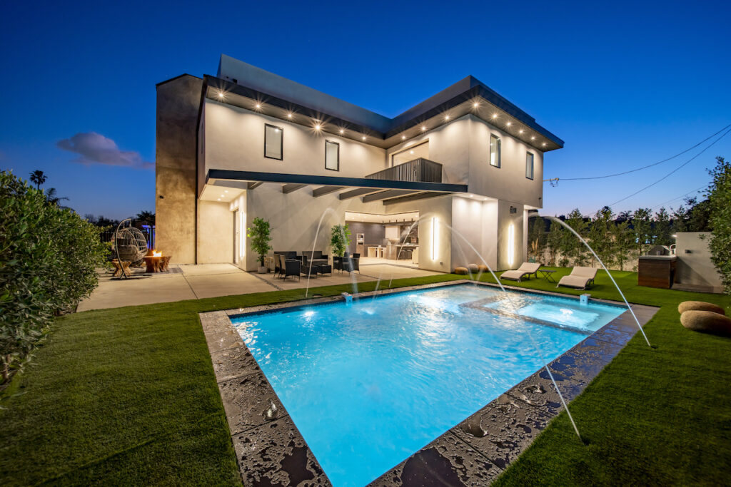 Modern luxury home exterior with pool at twilight.