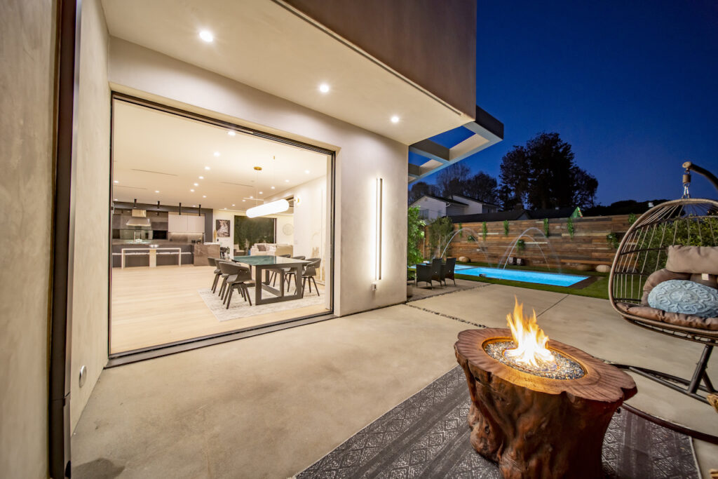 Modern home patio with fire pit and pool at dusk