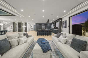 Modern spacious living room with kitchen and sunset view.
