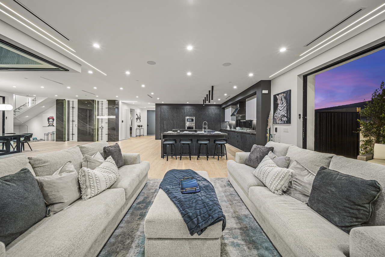 Modern spacious living room with kitchen and sunset view.